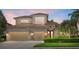 Charming two-story home featuring a three-car garage and beautifully manicured landscaping against a vibrant twilight sky at 6532 Coopers Hawk Ct, Lakewood Ranch, FL 34202