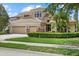 Stunning two-story home featuring a three-car garage, well-manicured lawn, and beautiful tropical landscaping at 6532 Coopers Hawk Ct, Lakewood Ranch, FL 34202