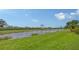 Scenic golf course view with a tranquil lake, lush greenery, and palm trees under a bright sky at 7019 Grand Estuary Trl # 101, Bradenton, FL 34212