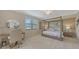 Serene main bedroom with a four-poster bed, plush carpet, and ample natural light from a large window at 7019 Grand Estuary Trl # 101, Bradenton, FL 34212
