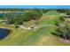 Aerial view of golfers on a lush course with mature trees and scenic water features on a sunny day at 7441 Myrica Dr, Sarasota, FL 34241