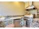 Outdoor kitchen features a stone backsplash, granite countertops, stainless steel grill and mini fridge at 7441 Myrica Dr, Sarasota, FL 34241