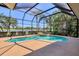 Screened-in pool area with a uniquely shaped pool, spa, and view of a beautiful pond at 7441 Myrica Dr, Sarasota, FL 34241