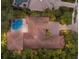 An aerial view of a private home with a unique pool, terracotta roof, and beautiful surrounding greenery at 7532 Greystone St, Lakewood Ranch, FL 34202