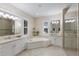 A luxurious bathroom featuring a large soaking tub, dual vanities, and a separate glass-enclosed shower at 7532 Greystone St, Lakewood Ranch, FL 34202