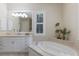 A bright bathroom featuring a soaking tub with light countertop, and white cabinets with framed mirrors at 7532 Greystone St, Lakewood Ranch, FL 34202