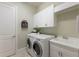 Functional laundry room with modern washer, dryer, white cabinets, and a utility sink at 7532 Greystone St, Lakewood Ranch, FL 34202