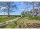 Beautiful backyard featuring a lush green lawn, mature trees, and a pathway leading to a serene beach at 7620 Westmoreland Dr, Sarasota, FL 34243