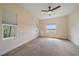 Spacious empty room featuring a ceiling fan, multiple windows and neutral carpet at 7743 Ridgelake Cir, Bradenton, FL 34203