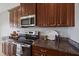 Close-up of the kitchen featuring granite countertops, stainless steel appliances, and dark wood cabinets at 7743 Ridgelake Cir, Bradenton, FL 34203
