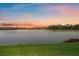Scenic lake view at sunset with colorful skies and lush green landscape, perfect for serene living at 7743 Ridgelake Cir, Bradenton, FL 34203