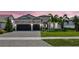 Charming home with a well-manicured lawn, stone accents, a three-car garage, and beautiful tropical landscaping at 8033 Grande Shores Dr, Sarasota, FL 34240