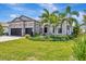 Elegant single-Gathering home featuring stone accents, a three-car garage, and lush tropical landscaping at 8033 Grande Shores Dr, Sarasota, FL 34240