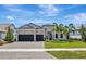 Charming home with a well-manicured lawn, stone accents, a three-car garage, and tropical landscaping at 8033 Grande Shores Dr, Sarasota, FL 34240