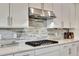Modern kitchen with a stainless steel range hood and a decorative backsplash set in white cabinets and drawers at 8033 Grande Shores Dr, Sarasota, FL 34240