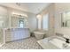 Light and bright bathroom featuring dual vanities, stand alone tub, and decorative floor tile at 8059 Waterbend Trl, Sarasota, FL 34240
