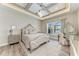 Luxurious main bedroom with decorative tray ceiling, chandelier, wood-look floors, and large window with backyard views at 8059 Waterbend Trl, Sarasota, FL 34240
