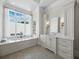 Elegant bathroom with a soaking tub, vanity with custom cabinets, and large window at 8155 Midnight Pass Rd, Sarasota, FL 34242