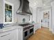 Chef's kitchen boasts a professional-grade range, custom hood, marble countertops, and white cabinetry at 8155 Midnight Pass Rd, Sarasota, FL 34242