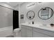 Modern bathroom features double sinks, round mirrors, white cabinets, and shower-tub combination at 8355 Velda Trl, Sarasota, FL 34241