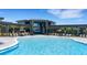 Community pool with lounge chairs and tables and umbrellas surrounding for sunbathing at 8355 Velda Trl, Sarasota, FL 34241