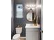 Compact powder room features a vanity with round mirror, modern lighting, and a toilet at 8355 Velda Trl, Sarasota, FL 34241
