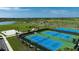 Aerial view of multiple community tennis courts, complemented by lush green surroundings and a nearby lake at 8355 Velda Trl, Sarasota, FL 34241