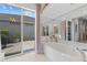 Bright bathroom with a large soaking tub, mirrored wall, and access to the outdoor patio at 8630 51St E Ter, Bradenton, FL 34211
