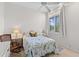 Bright bedroom features a floral quilt, wood chair, ceiling fan, and window at 8630 51St E Ter, Bradenton, FL 34211