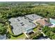 Aerial view of well-maintained tennis courts with covered seating areas, surrounded by lush landscaping and community amenities at 8630 51St E Ter, Bradenton, FL 34211