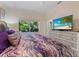 Comfortable bedroom featuring a television, and a picturesque view of verdant foliage through the window at 8687 Woodbriar Dr, Sarasota, FL 34238