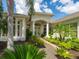 Inviting home entrance featuring an arched entryway, white columns, and lush tropical landscaping at 8687 Woodbriar Dr, Sarasota, FL 34238