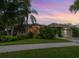 Charming home exterior with lush landscaping and a beautiful sunset backdrop at 8687 Woodbriar Dr, Sarasota, FL 34238