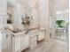 A luxurious bathroom with double sinks, marble countertops, and a view into a garden tub at 8687 Woodbriar Dr, Sarasota, FL 34238
