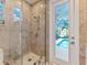 Walk-in shower with seamless glass doors and a door to a patio and pool view in neutral tones at 8687 Woodbriar Dr, Sarasota, FL 34238