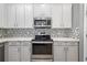 Contemporary kitchen featuring white cabinets, stainless steel appliances, and a stylish backsplash at 9307 Raes Creek Pl, Palmetto, FL 34221