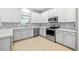 Modern kitchen featuring stainless steel appliances, white cabinets, and designer backsplash at 9307 Raes Creek Pl, Palmetto, FL 34221