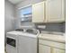 Functional laundry room with modern washer, dryer, sink, and cabinet storage at 9307 Raes Creek Pl, Palmetto, FL 34221