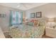 Comfortable bedroom with blue curtains, ceiling fan, and floral bedding at 9320 Clubside Cir # 2208, Sarasota, FL 34238