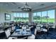 Elegant dining area with large windows showcasing golf course views and stylish chandelier lighting at 9320 Clubside Cir # 2208, Sarasota, FL 34238