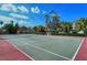 Well-maintained tennis court surrounded by tropical greenery and clear blue sky at 9320 Clubside Cir # 2208, Sarasota, FL 34238
