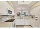 Open kitchen view into living space with white appliances, stone countertops, and stainless steel features at 9641 Castle Point Dr # 1215, Sarasota, FL 34238