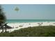 Sandy beach view with beachgoers, palm trees, and blue ocean water at 1255 E Peppertree Dr # 506, Sarasota, FL 34242