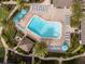 Aerial view of the community pool with umbrellas, lounge chairs, and lush landscaping at 1255 E Peppertree Dr # 506, Sarasota, FL 34242
