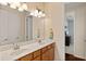 Bright bathroom with double sink vanity, large mirror, and doorway to an adjacent room at 13409 Ramblewood Trl, Bradenton, FL 34211