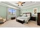 Bright bedroom with tray ceiling, ceiling fan, sitting area, and large window providing lots of natural light at 13409 Ramblewood Trl, Bradenton, FL 34211