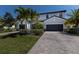 Inviting two-story home with a two-car garage, paver driveway, lush landscaping and palm trees enhances curb appeal at 13409 Ramblewood Trl, Bradenton, FL 34211