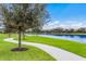 Scenic paved walking path alongside a lake with views of residential homes and lush landscaping at 13409 Ramblewood Trl, Bradenton, FL 34211