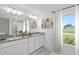 Bright bathroom featuring double vanity, granite countertops, and natural light from a large window at 16206 Arcaro Ave, Port Charlotte, FL 33954