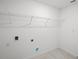 Clean laundry room showcasing hookups and overhead shelving for optimal organization at 16206 Arcaro Ave, Port Charlotte, FL 33954